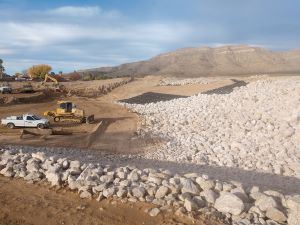 Large rocks support the edges of a dirt channel.