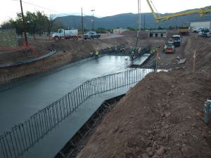 Construction workers pouring cement in a large ditch