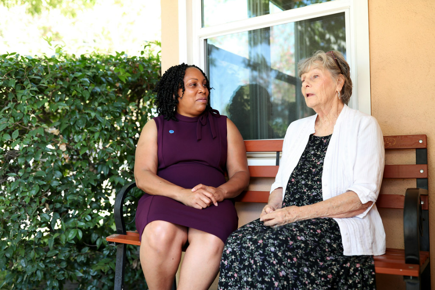 Two women sit together on a bench.